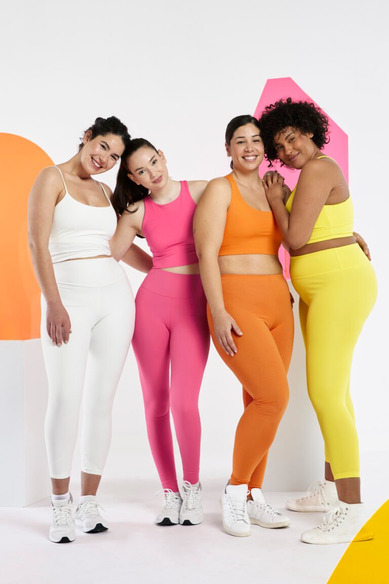 Three fit women posing in stylish workout outfits in a studio – showcasing trendy activewear fashion for 2025